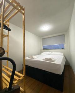 Un dormitorio con una cama con sábanas blancas y una escalera en Cacau Tiny House, en Itacaré