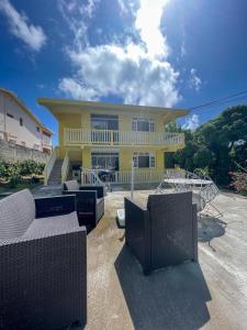 a yellow house with chairs and tables in front of it at Villa trinité in La Trinité
