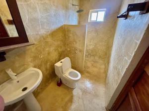 a bathroom with a white toilet and a sink at Kite Active Paje in Paje