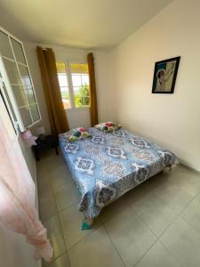 a bedroom with a bed with a blue and white quilt at Villa trinité in La Trinité +1 photo