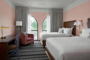 a hotel room with two beds and a chair at The Memphian a Tribute Portfolio Hotel in Memphis