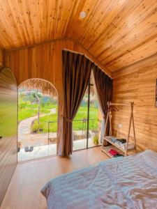 a bedroom with a bed and a large window at Bó Bun Homestay Mộc Châu in Mộc Châu