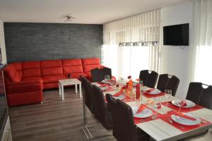 a dining room with a table and a red couch at Haus Bergtreu in Saas-Grund