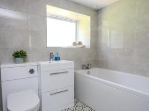 a bathroom with a white tub and a toilet and a sink at Golygfa Rhiw in Pwllheli +33 photos