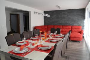 a dining room with a table and a red couch at Haus Bergtreu in Saas-Grund