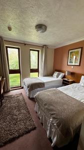 a hotel room with two beds and two windows at Farmhouse Inn in Thaxted