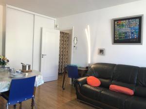 ein Wohnzimmer mit einer schwarzen Ledercouch und einem Tisch in der Unterkunft LE CASINO DES FLEURS - Hypercentre - Parking - Balcon in Vichy + 6 Fotos