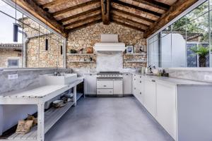 a kitchen with white appliances and a brick wall at Secret d'Uzès - Le Duché - Piscine chauffée et Jacuzzi in Uzès