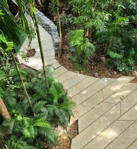 a wooden walkway through a garden with palm trees at hiddenwoods in Bang Chak