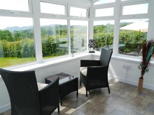 a room with a table and chairs and windows at Swallow Cottage in Dalbeattie
