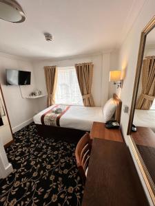 a hotel room with a king sized bed and a desk at Andorra Guest Accommodation in Brighton & Hove