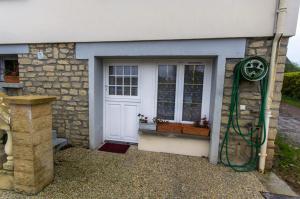 a house with a white door and a green hose at A 1Okm des plages du débarquement, Chez Sabrina, gîte entre mer et campagne, proximité Caen, Bayeux, Arromanches, aéroport Carpiquet in Lantheuil