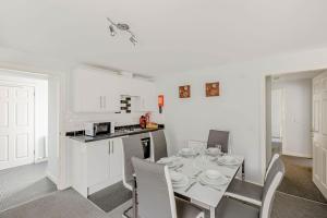 a white kitchen with a table and chairs in a room at Auchenlarie Courtyard No 3 in Gatehouse of Fleet +20 photos