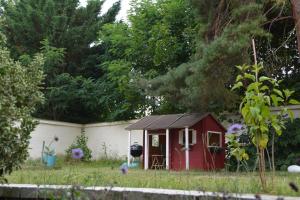 a red shed in the middle of a yard at Bel appartement neuf proche de Paris in Maisons-Laffitte