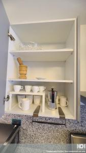a kitchen with white shelves with bowls and dishes at Exclusivo céntrico en la Trinitaria in Santiago de los Caballeros