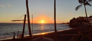 a sunset on a beach with palm trees and the ocean at Atardecer Azul in Puerto Naos