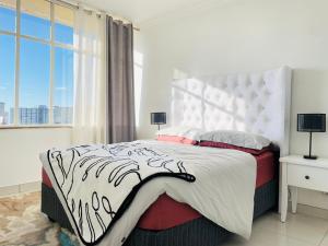 a white bedroom with a large bed and a window at Villa Saarchi Apartments in Windhoek