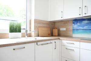 ヴィットムントにあるStudio 20 Ostfrieslandのシンクと窓のある白いキッチン
