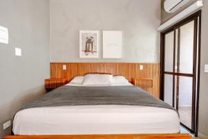 a bedroom with a large bed with a wooden headboard at JQY Beach Flats - 950m da Praia - Garagem subterrânea - Estação de carregamento para veículos elétricos in Juquei