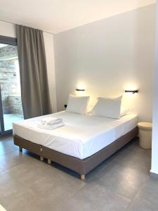 a bedroom with a bed with white sheets and pillows at Spanos Apartments in Agios Petros