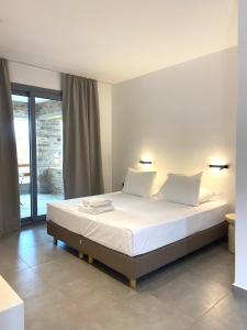 a bedroom with a bed with white sheets and pillows at Spanos Apartments in Agios Petros