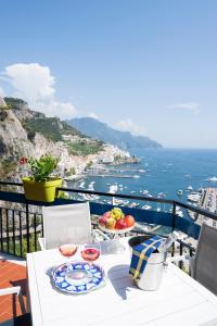 una mesa con platos de comida en un balcón con vistas al océano en Skyview Paradise House, en Amalfi