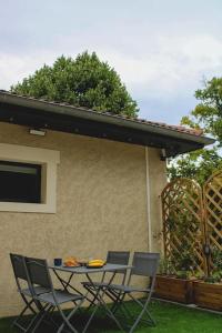 Una mesa y sillas frente a un edificio. en Appartement Gîte des 3 Enfants, en Montluel