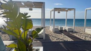 a beach with white umbrellas on the beach at Poetto Casa Bach Ck in Quartu SantʼElena