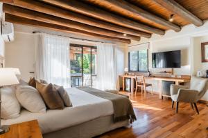 a bedroom with a large bed and a desk with a television at Lares De Chacras in Chacras de Coria