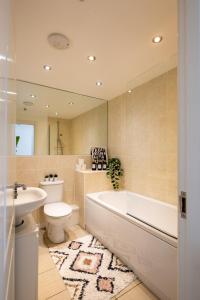 a bathroom with a tub and a toilet and a sink at Cozy Glam Patchway Garden House Sleep 9 Mid-Long Term Welcome in Bristol +52 photos