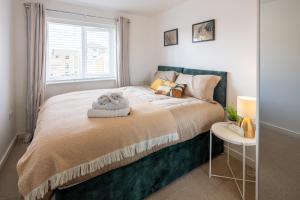 a bedroom with a large bed and a table at Cozy Glam Patchway Garden House Sleep 9 Mid-Long Term Welcome in Bristol