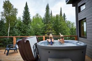 two children playing in a hot tub on a deck at Maison contemporaine Tremblant- Spa & tranquillité in Lac-Superieur