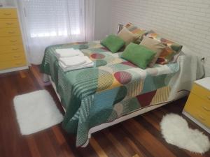 a bedroom with a bed with a colorful blanket and pillows at El nido de lu in Vilagarcia de Arousa