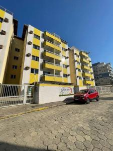a red car parked in front of a building at Recanto das Ondas in Ubatuba