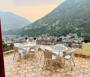 a group of tables and chairs on a balcony with a view at Kullu Manali Homestay in Kulu