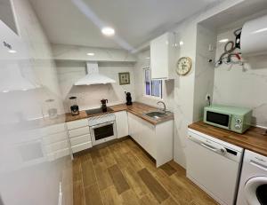 a kitchen with white cabinets and a microwave at 100 metros playa vistas al mar Piso nuevo in Cullera +20 photos