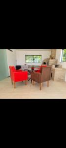 a living room with two red chairs and a table at Fazenda de Jehne in Camamu