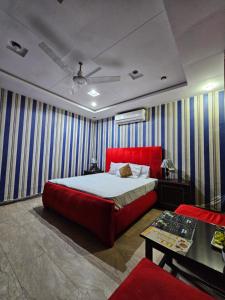 a bedroom with a red bed and striped walls at Hotel Tulip Inn, Gulberg in Lahore
