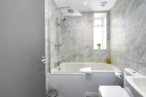 a bathroom with a tub and a toilet and a sink at Diamond House - 4 bedroom luxury home in Airdrie +8 photos