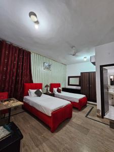 two beds in a hotel room with red furniture at Hotel Tulip Inn, Gulberg in Lahore