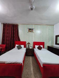 two beds in a hotel room with red curtains at Hotel Tulip Inn, Gulberg in Lahore