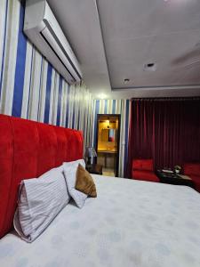 a bedroom with a bed with a red head board at Hotel Tulip Inn, Gulberg in Lahore