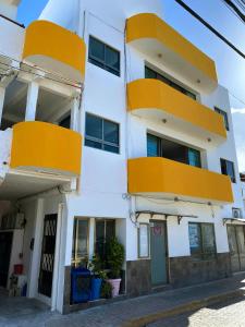 a white building with orange balconies on a street at Departamentos Maya in Isla Mujeres