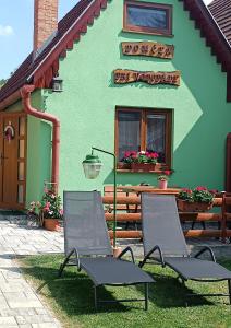two chairs sitting in front of a green building at Domček pri vodopáde in Lúčky