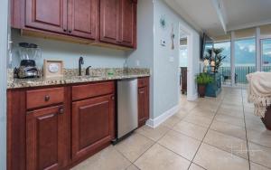 a kitchen with wooden cabinets and a tile floor at Phoenix Gulf Shores 1602-2 condo in Gulf Shores