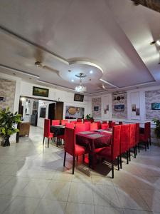 a dining room with red chairs and tables in a restaurant at Hotel Tulip Inn, Gulberg in Lahore