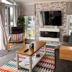 a living room with a fireplace and a tv at Rolo's Lakeside Lodge With Hot Tub & Hi-Speed Wifi in Stamford