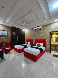 two beds in a room with red furniture at Hotel Tulip Inn, Gulberg in Lahore