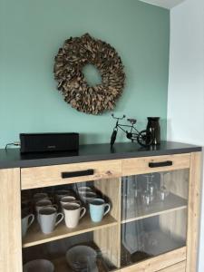 a wooden cabinet with cups and a wreath on the wall at Rathauswiese Ferienwohnung in Braunlage