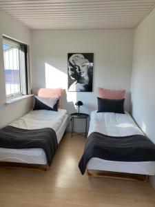 two beds in a white room with a window at Lejlighed i naturskønt område in Bratten Strand